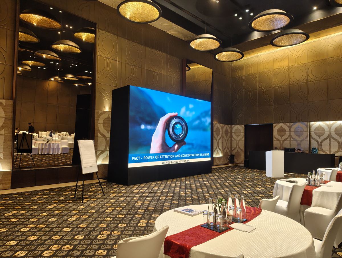 Hotel ballroom set up for a PACT session with the program on a large LED screen